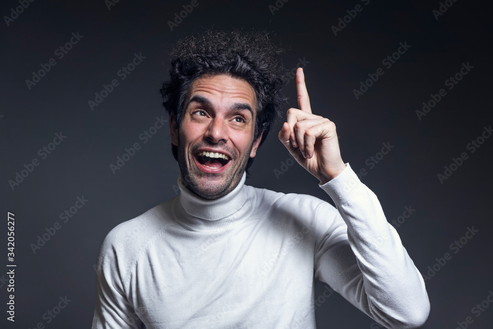 Portrait of an excited casual curly man with new ideas standing with raised hand Portrait of an excited casual curly man with new ideas standing with raised hand