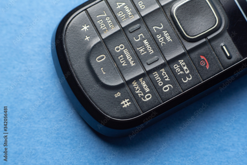 old push-button cell phone on blue background old push-button cell phone on blue background