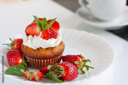 Homemade muffins with fresh strawberries on white plate. Homemade tasty dessert or breakfast. Healthy eating concept