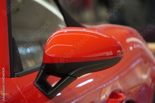 Rearview mirror of a red sport car  glare from the sun in the glass of the car. Highlights on the body of a red supercar