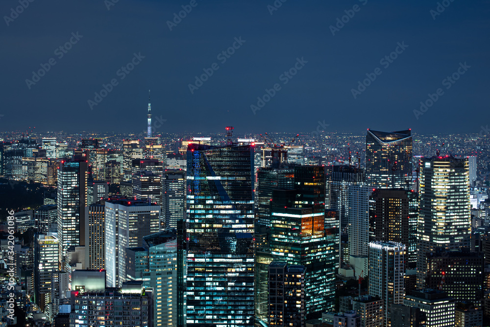 Night city view. Buildings skyline urban panorama. Light in windows. Narrow view.