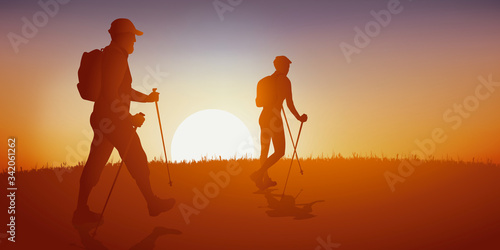 Concept de la randonnée avec un homme et une femme qui se promène en faisant de la marche nordique sur un chemin de campagne.
