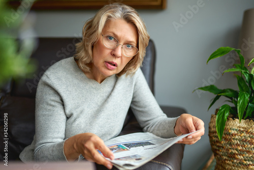 Fotografie news, press, media, holidays and people concept - woman reading newspaper at hom