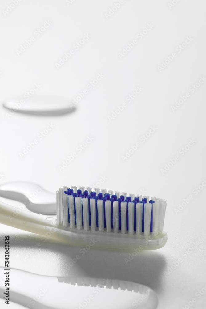 A white and blue toothbrush over a wet white background for oral hygiene concepts. A white and blue toothbrush over a wet white background for oral hygiene concepts.