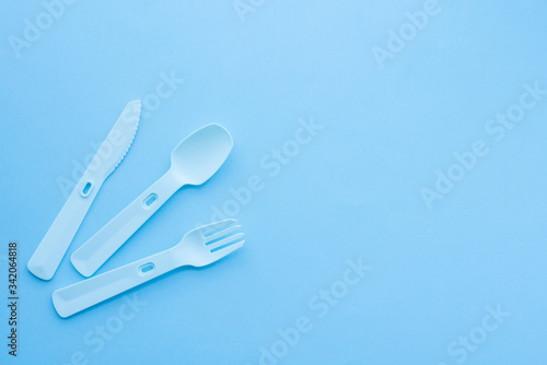 Plastic dishes  disposable tableware  plates  glasses  spoons  forks on a blue background. Caring for the environment. The problem is recycling. Reuse  safe planet  environmental concept. 