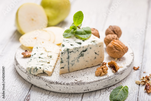 Segment of blue mould cheese - Gorgonzola with pear and walnuts on wooden board.  Top view photo