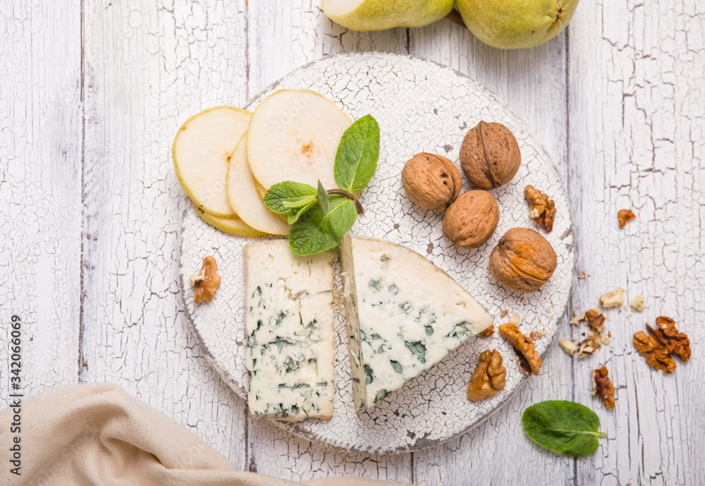 Segment of blue mould cheese - Gorgonzola with pear and walnuts on wooden board.  Top view