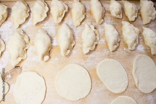 National Russian cuisine. Pierogi or pyrohy, vareniki, served with cottage cheese and potatoes on board. Raw dumplings made of dough in handmade flour