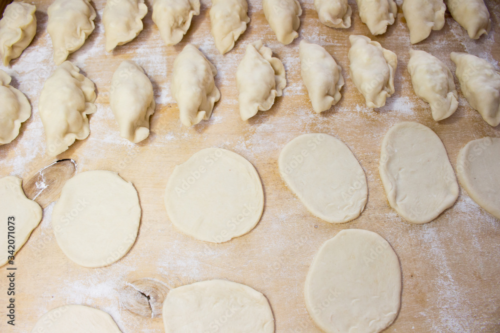 National Russian cuisine. Pierogi or pyrohy, vareniki, served with cottage cheese and potatoes on board. Raw dumplings made of dough in handmade flour National Russian cuisine. Pierogi or pyrohy, vareniki, served with cottage cheese and potatoes on board. Raw dumplings made of dough in handmade flour