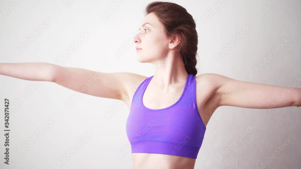 Young female yogi is concentrated in pose. Looking at the hand while performing an asana. Self-isolated at home Young female yogi is concentrated in pose. Looking at the hand while performing an asana. Self-isolated at home