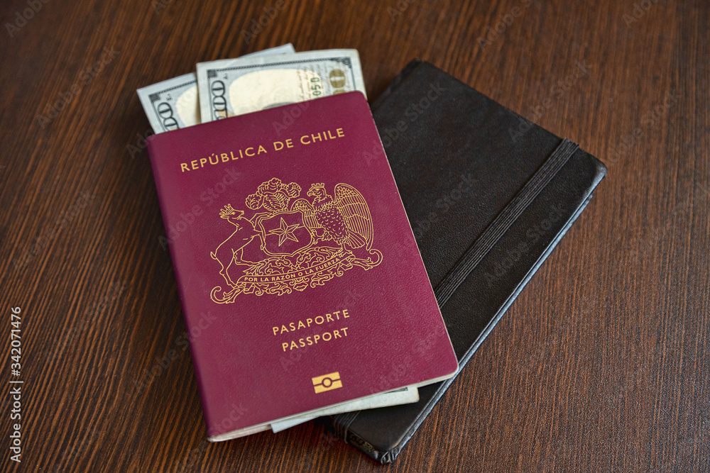 One Red Chilean passport with some dollars on a deskc table