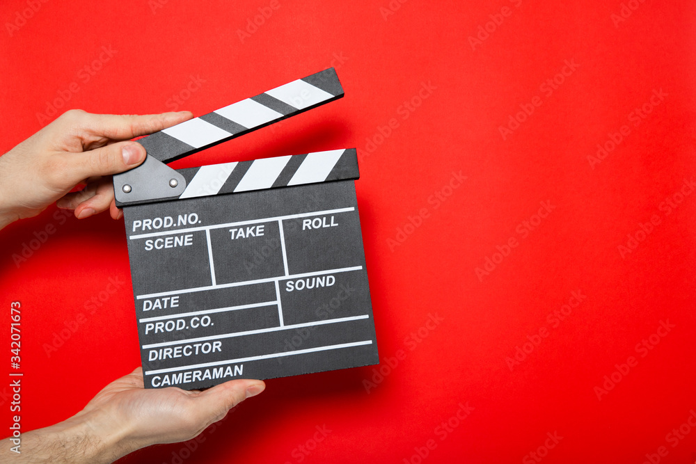Movie clapper in the hands of a guy on a red background with place for text