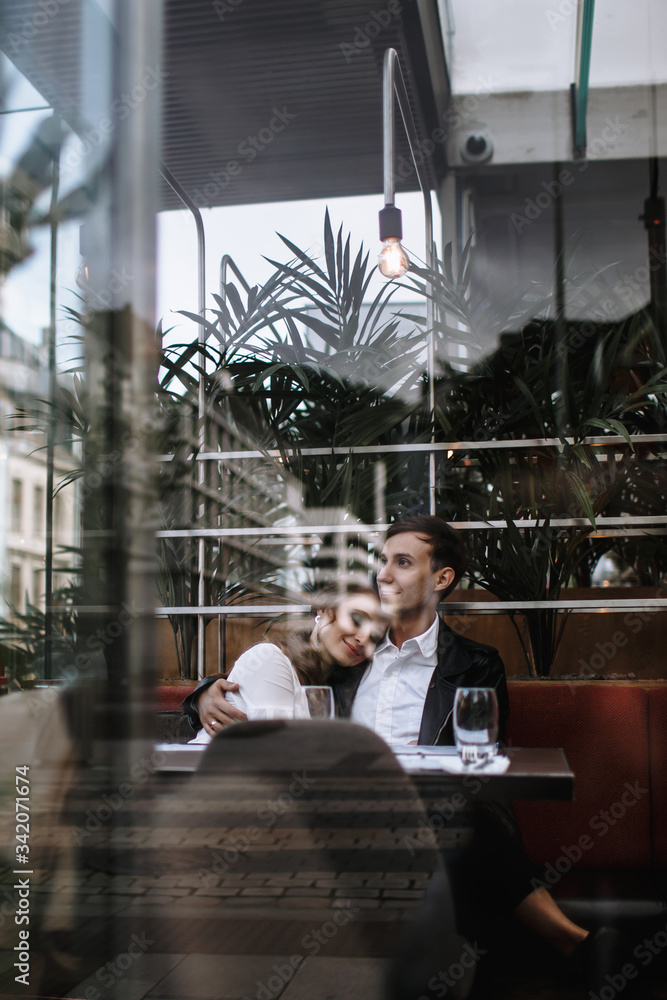 A couple in love sitting in a cafe. Photo taken through the glass of the restaurant