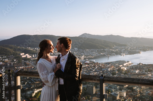 Two lovers standing on the observation deck of Bergen, Norway, against the background of the sunset