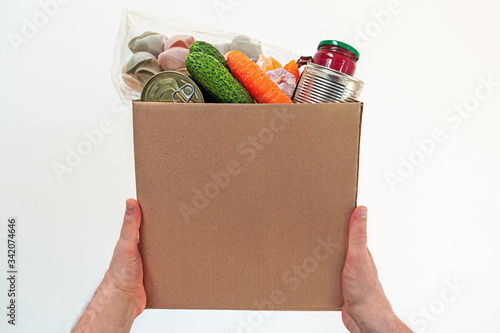 Food delivery service - male hands with a box of fresh food on a white background with copy space. Donation box.