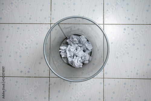 Crumpled papers in metallic mesh trash can