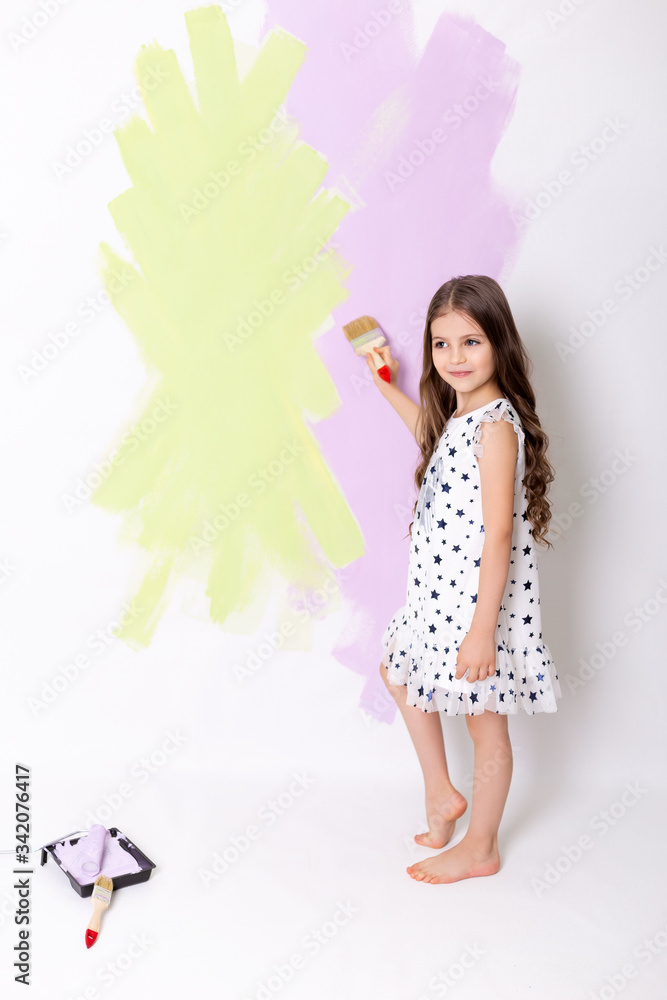 Little girl drawing something using painting brush on wall background. Little girl drawing something using painting brush on wall background.