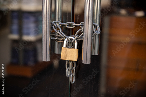 Closed Store due to Coronavirus pandemic. Locked Store Door with Padlock and Chains
