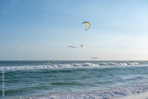 Birds and kiteboarders against the blue sky on the beach in Rio de Janeiro, Brasil. Ocean and sky.