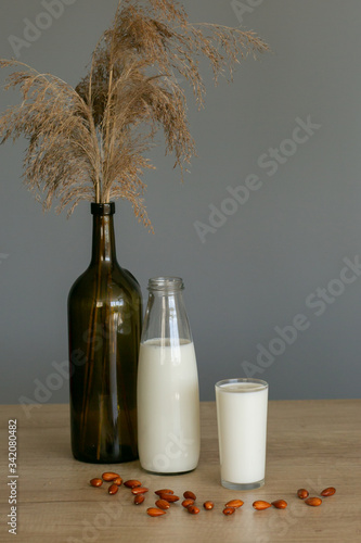 High angle view almond and milk in white bowl on wooden textured background. Various vegan plant based milk and ingredients , top view, copy space. Dairy free milk substitute drink, healthy eating