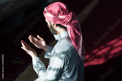 Young Arabic Muslim man  praying. Doing a dailly pray inside modern beautiful mosque. photo