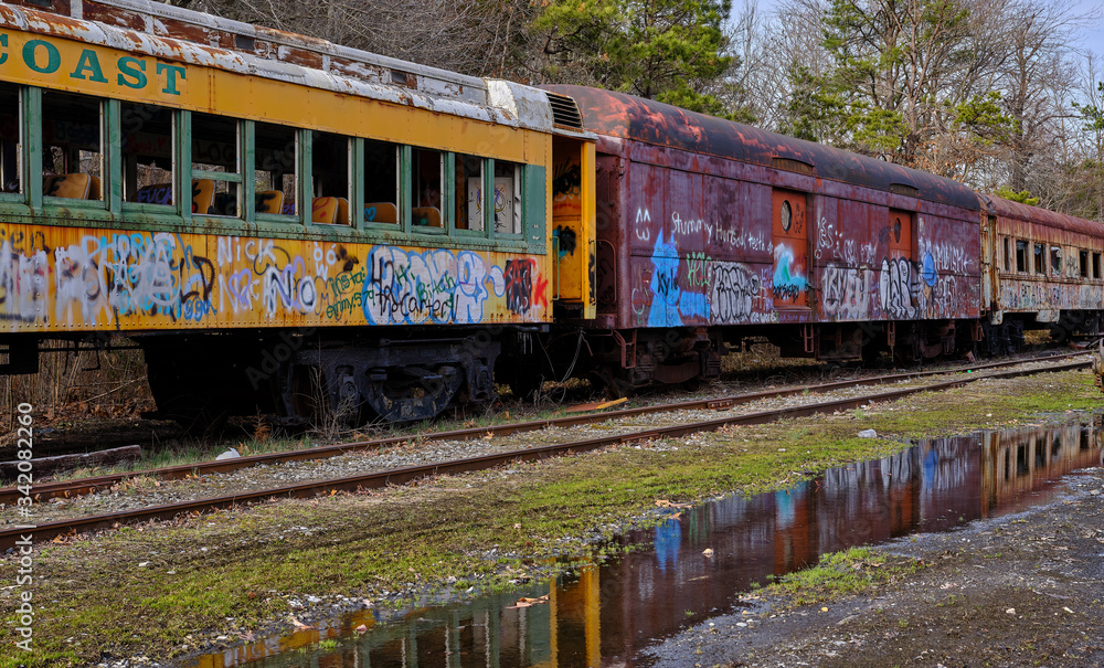 abandoned railroad train cars reflected in rain puddles