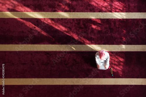 Young Arabic Muslim man  praying. Doing a dailly pray inside modern beautiful mosque. photo