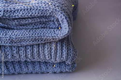 Background or texture of blue hand-knitted plaid and pillows in cosy autumn or winter home.