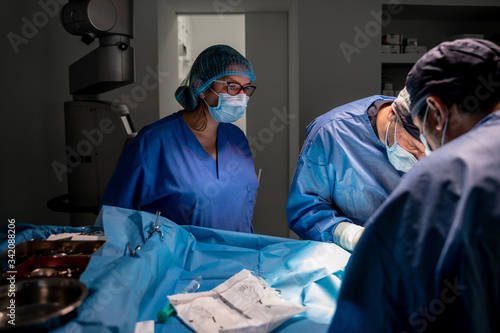 Surgeons and nurses in uniform concentrating and operating patient using special equipment in operating room of contemporary hospital
