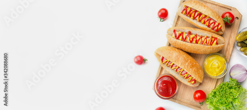 Hot dog with pickles, tomatoes and lettuce on a light background. Fast food. Calorie content of food. View from above. Space for copy. Food banner.