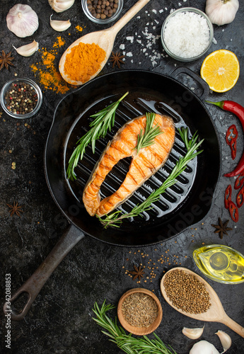Salmon steak in a grill pan with spices on a dark table. Seafood. Cooking concept. Culinary background. Flat lay.