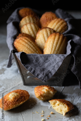 Traditional yummy homemade Madeleine cookies placed on black container with napkin on wooden table photo