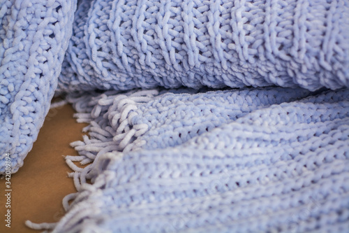 Background or texture of blue hand-knitted plaid and pillows in cosy autumn or winter home.