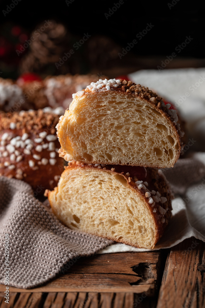 Top view of appetizing cut homemade round bread with hole decorated with sprinkles and cherry placed on wooden table with Christmas decoration Top view of appetizing cut homemade round bread with hole decorated with sprinkles and cherry placed on wooden table with Christmas decoration