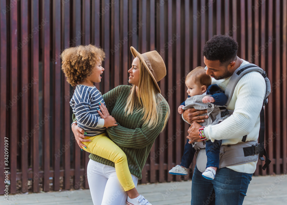 © Gabriel Trujillo/ADDICTIVE STOCK - Cheerful stylish young multiracial couple with infant son and little daughter in casual wear walking together along wooden fence on city street © Gabriel Trujillo/ADDICTIVE STOCK - Cheerful stylish young multiracial couple with infant son and little daughter in casual wear walking together along wooden fence on city street