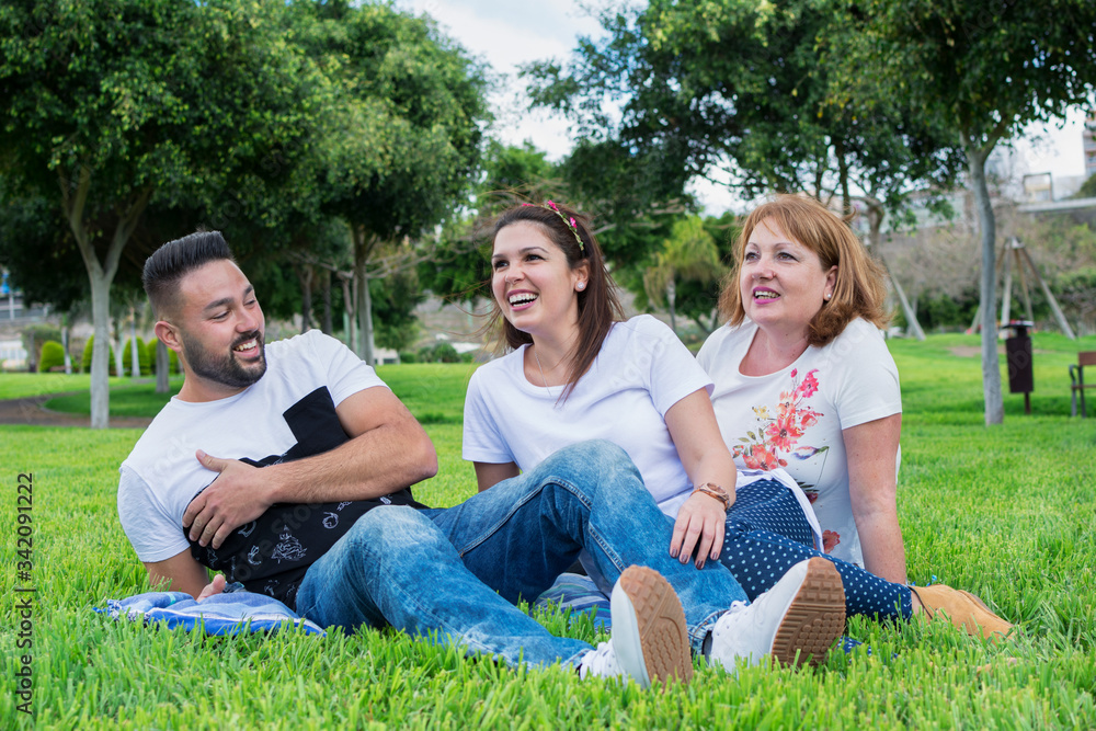 Two brothers boy and girl with their mother happy and laughing sitting on the green grass of the park. Two brothers boy and girl with their mother happy and laughing sitting on the green grass of the park.