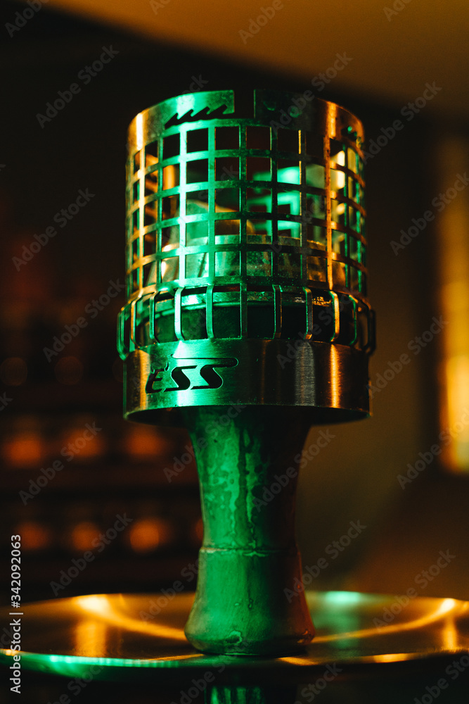 Hot hookah coals in a bars on tobacco bowl close up in green neon light Hot hookah coals in a bars on tobacco bowl close up in green neon light