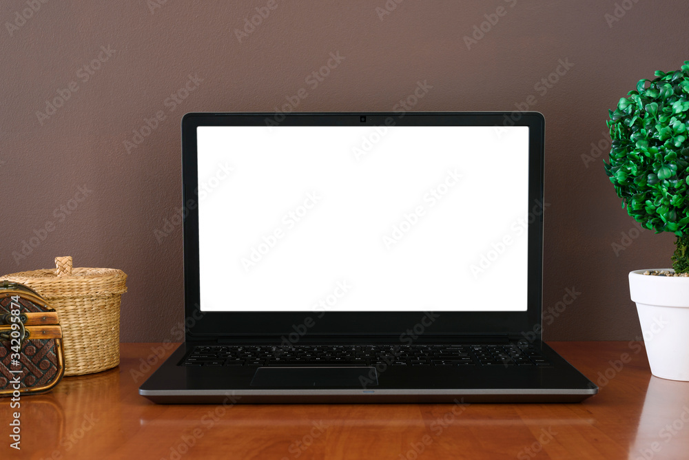 Work space - open laptop with mockup on screen. Wooden containers and green plant in pot. Background of brown wall. Work space - open laptop with mockup on screen. Wooden containers and green plant in pot. Background of brown wall.