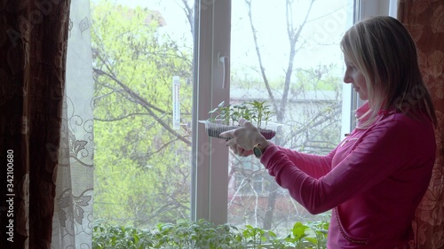 A young woman cares for the plants growing in her house