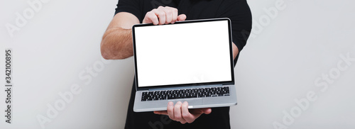 Close-up of male hands holding opened laptop with mockup on screen, panoramic banner background of white.