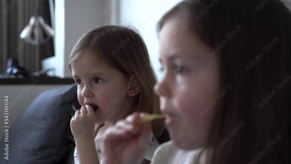 Family eating chips and watching tv. Two sisters eat unhealthy food Family eating chips and watching tv. Two sisters eat unhealthy food