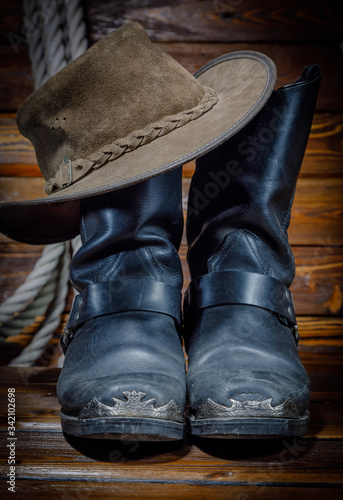 cowboy hat, boots and rope on wooden background