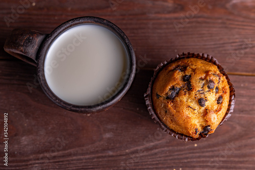 clay mug with milk and muffin on a wooden table