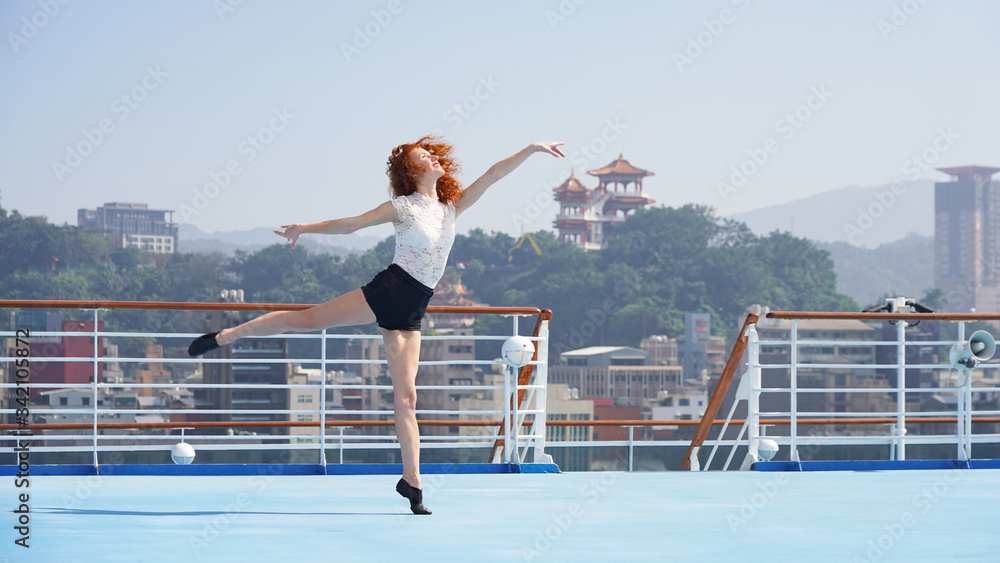 Ballerina dancer. A beautiful graceful slim ballerina performs a delicate dance on her fingers in black dance shoes on a blue background. Classic dance position. Model woman on a cruise ship in Asia.