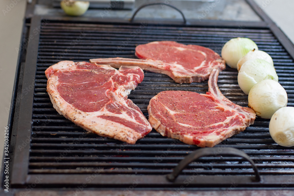 Some pieces of sirloin steak and some green onions on a grill 