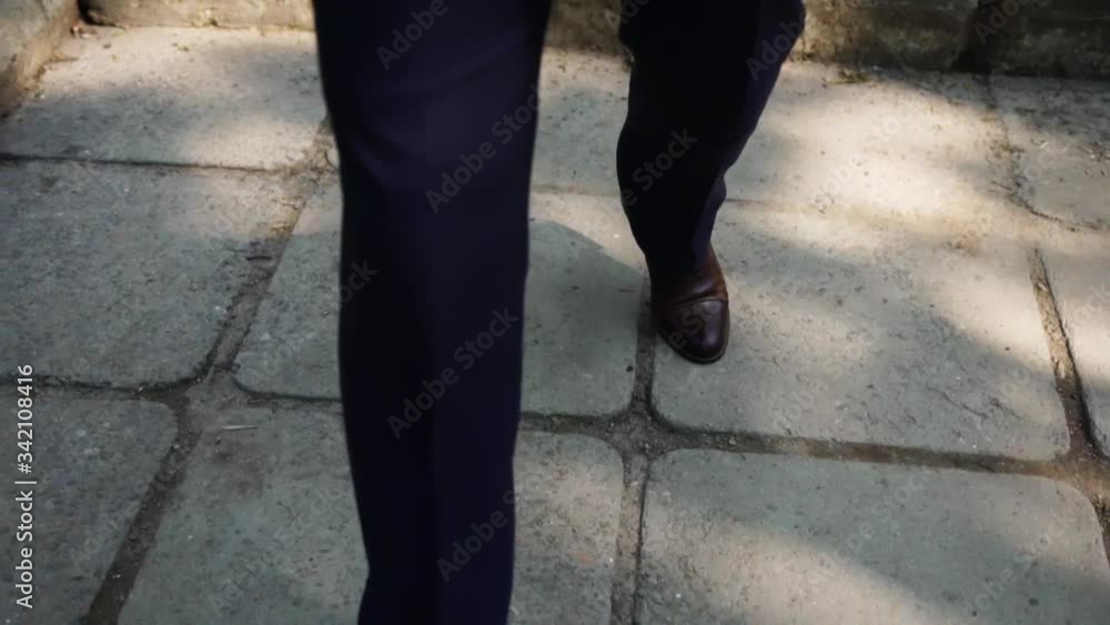 А man in a solid suit walks along a path and gatherings А man in a solid suit walks along a path and gatherings