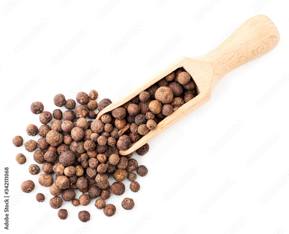 Dry allspice in a wooden spatula on a white background. The view from top Dry allspice in a wooden spatula on a white background. The view from top