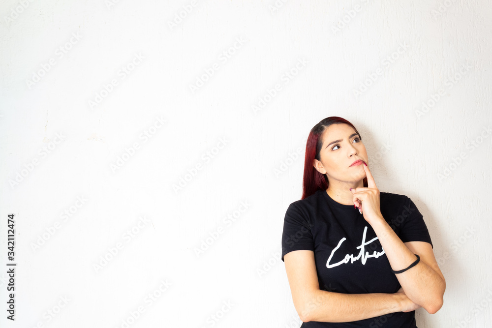 Hispanic redhead woman pensive and doubting on a white background Hispanic redhead woman pensive and doubting on a white background