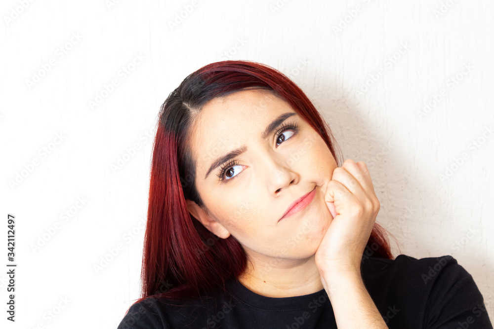 Hispanic redhead woman pensive and doubting on a white background Hispanic redhead woman pensive and doubting on a white background