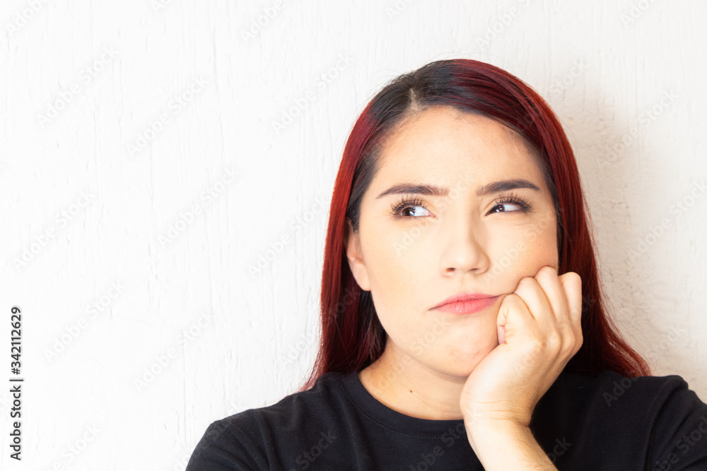 Hispanic redhead woman pensive and doubting on a white background Hispanic redhead woman pensive and doubting on a white background
